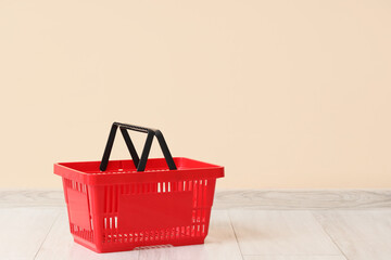 Red shopping basket near beige wall