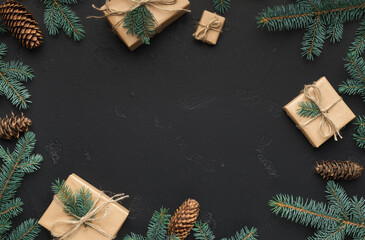 Christmas frame of fir branches, presents and cones on black background