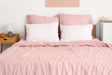 Obraz premium Bed with stylish pink bedding and bedside table in bedroom
