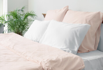 Bed with stylish pink bedding and houseplant in bedroom