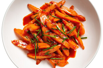 Roasted carrot sticks tossed in a savory sauce, garnished with green herbs