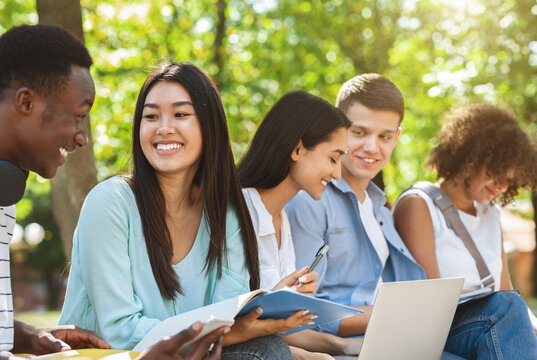Cheerful university friends resting beetween classes outdoors, chatting and laughing, copy space