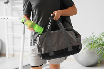 Man with water bottle and sports bag at gym