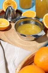 Freshly squeezed orange juice, fruits, juicer and towel on table, closeup