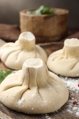 Uncooked khinkalis (dumplings) on wooden table, closeup