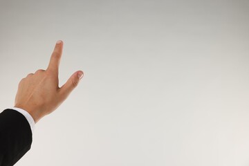 Man touching something on light grey background, closeup. Space for text