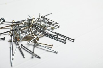 Different metal nails on white wooden table, closeup. Space for text