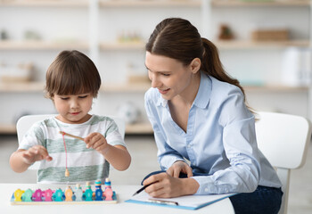Early development concept. Happy little boy playing with wooden fishing game during psychological...