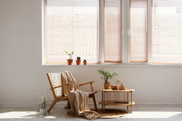 Interior of living room with wooden wicker armchair, coffee table and houseplants on windowsill