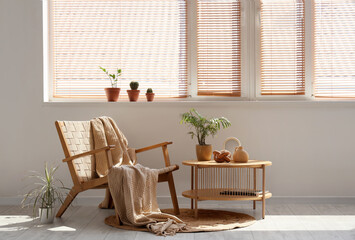 Interior of living room with wooden wicker armchair, coffee table and houseplants on windowsill