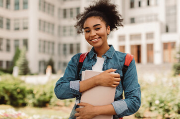Portrait Of Successful Student. Happy African American Teenager Girl Posing Holding Books Smiling...