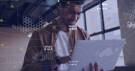 Tech professional holding silver laptop displaying overlaid data graphics in office with smartwatch