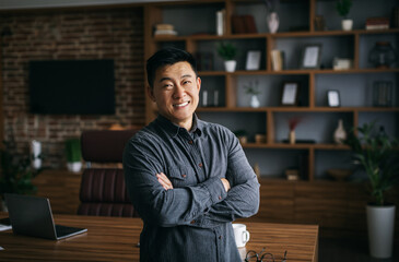 Happy confident handsome mature japanese businessman with crossed arms on chest in dark cabinet...