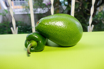 Pimentón y Aguacate de color verde colocados en una ventana con un fondo desenfocado.