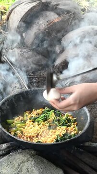 A person cooking traditional Indonesian seblak in the middle of a lush rice field, combining authentic street