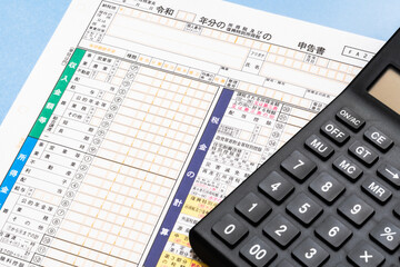 確定申告書と電卓を使った税金計算のイメージ