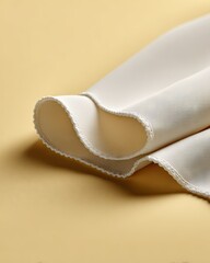 Soft white fabric draped on a pale yellow surface