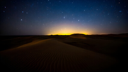 Desert sand dunes under starry night sky with distant yellow glow image