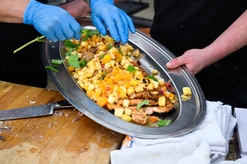 Grilled king salmon on a stainless steel platter with chef’s covering with diced tropical fruits at a finish, part of luau dinner preparations 
