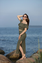 Smiling woman in green dress posing by sea