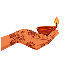 Womans hand with henna mehndi holding a lit diya oil lamp.