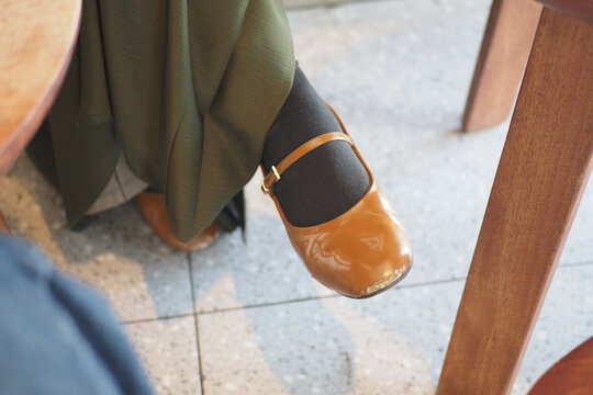 Brown leather shoe worn by person seated at table