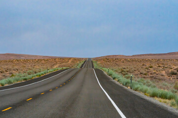 Long Desert Highway Winding Towards Horizon Under Overcast Sky