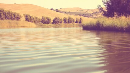 Picturesque lake view with rolling hills and serene water ripple creating a tranquil scene