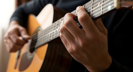 Fototapeta premium Close-up of a person's hands playing an acoustic guitar with warm, natural light illuminating the warm wood tones and detailed frets.