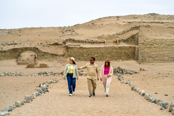 Tourists exploring pre inca ruins with tour guide in peruvian desert