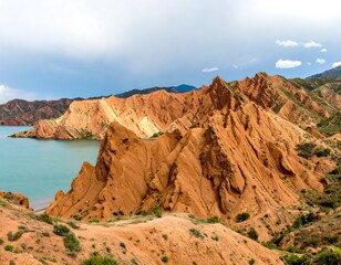 Fototapeta premium Colorful sandstone cliffs overlooking a tranquil lake under a cloudy sky
