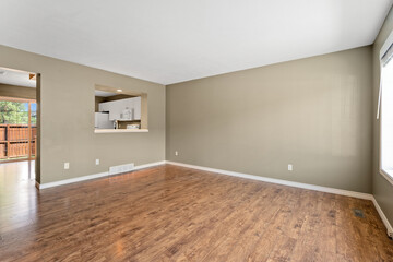 Large, empty living room with a kitchen area