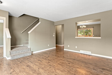 Large, empty living room with a staircase leading up to the second floor