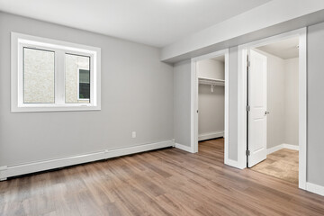 Large, empty room with a window and a closet