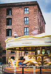 Obraz premium An example of slow shutter speed photography, showing the moving carousel against the brick building.