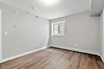 Very clean and empty room with a wooden floor and a window