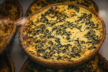 A close-up of a freshly baked spinach quiche showcases its golden-brown crust and enticing top...