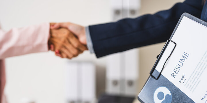 employer hr with employment contract job on desk officer hiring welcoming female asian newcomer worker manager shaking hands in contemporary office. Getting new job handshake concept.