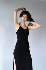 Fototapeta premium young beautiful woman posing in black dress in studio