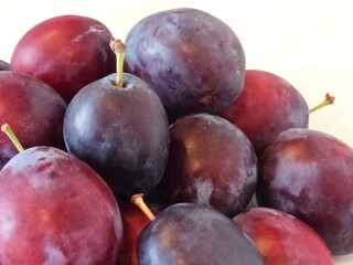 Fresh plums with water droplets on the surface. The plums look fresh, with visible water droplets, which may indicate recent washing or dew.