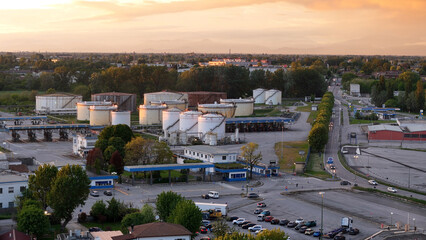 Aerial drone perspective revealing Iron Bridge viaduct near Cremona, intersecting industrial landscape with oil refinery during golden hour sunset lighting