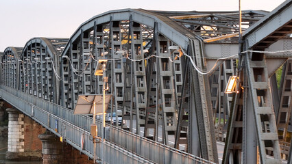 Iron bridge spanning Po River near Cremona, Italy, connecting road and railway networks under warm sunset lighting, captured from aerial drone viewpoint