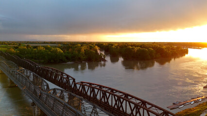 Aerial view of historic Iron Bridge crossing Po River during golden sunset, revealing architectural...