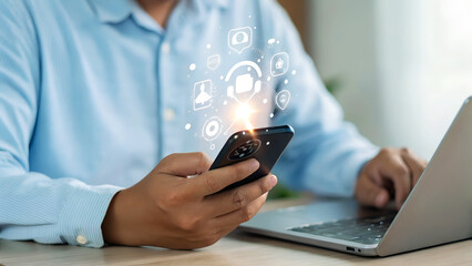 Professional using smartphone for seamless collaboration and social media engagement while working from a laptop, enhancing digital communication effortlessly