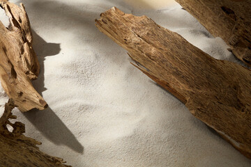 A clean frame showing wood on sand, captured with soft light to highlight textures, ideal as a backdrop for herbal product styling.