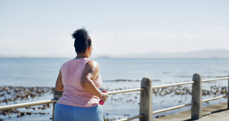 Running, dumbbell and back of plus size woman at beach for workout, cardio challenge and health....
