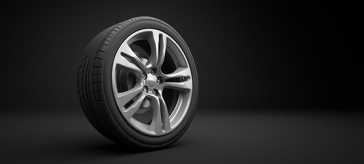 Obraz premium Silver rim with black tire on isolated dark studio backdrop, showcasing sleek automotive design and contrasting textures