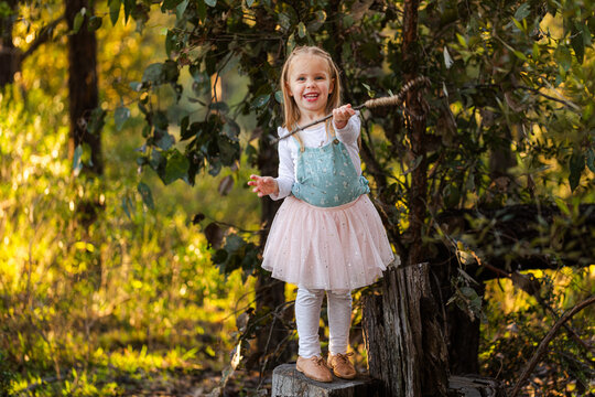 little kid playing in Australian forest with homemade magic wand and fairy dress