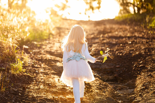child holding homemade magic wand made of gum nuts off on an adventure through bushland