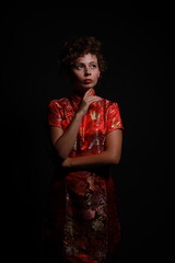 Low key portrait of young brunette woman in red dress